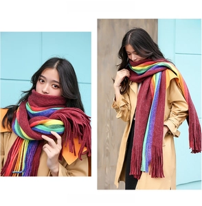 Close-up of rainbow striped knit scarf with long fringe paired with a trench coat