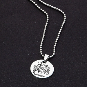 Macro shot of silver stainless steel pendant with Best Teacher engraving and bead chain