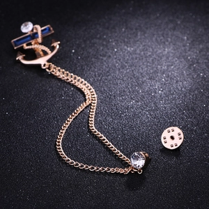 Detailed macro view of golden anchor brooch with blue crystals and vintage tassel chain