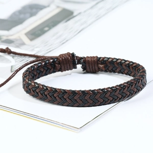 Close-up of multi-layer woven leather bracelet in dark brown and black tones on a magazine