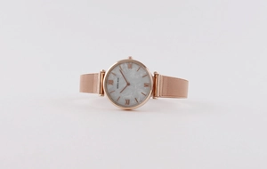 Close-up of rose gold mesh band watch with white marble dial and Roman numerals