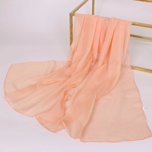 Sciarpa lunga in chiffon arancione esposta su un supporto in metallo dorato fine