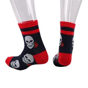 Détail de chaussettes en tricot avec motif tête de mort et rose sur fond noir uni