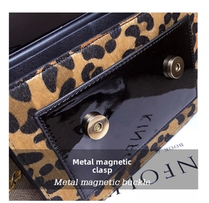 Close-up of leopard print crossbody bag featuring glossy black flap and dual metal magnetic snaps