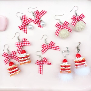 Detail showing red plaid bow earrings with faux pearls and plush pompom charms