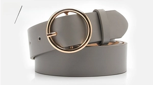 Detail of gray leather belt with shiny gold round buckle for women's casual jeans
