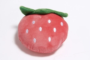 Detailed close-up of a strawberry-shaped plush dog toy with soft red fabric and green leaves