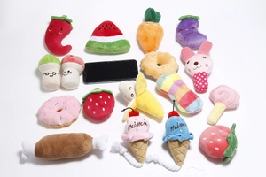 Flat lay of colorful plush pet toys featuring fruit and food shapes on white background