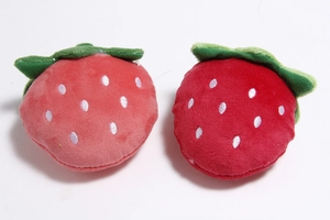 Detail view of two plush strawberry pet toys in pink and red with soft fabric textures