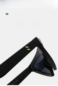 Detail view of glossy black sunglasses frame with golden metal hinges and rivets