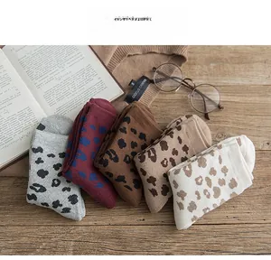 Flat lay of five pairs leopard print thermal crew socks with vintage books and glasses
