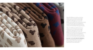 Close-up of thick knit socks featuring leopard and heart patterns in diverse warm colors