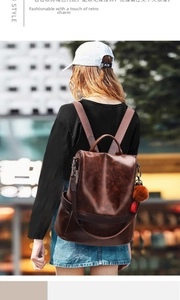 Brown leather backpack with anti-theft back zipper and pompom charm on a model