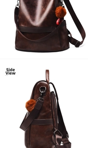 Close-up of deep brown pebbled leather backpack with side pocket and orange pompom charm