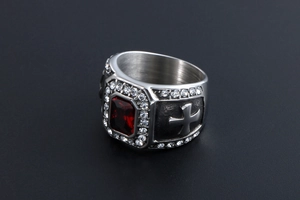 Gros plan détaillé d'une bague vintage argentée avec pierre rouge et motifs de croix