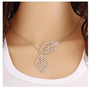 Close-up of silver necklace featuring two delicate hollow leaf pendants on a female model