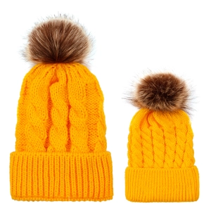 Detail of yellow knit cable hats with faux fur pompons for mother and child