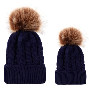 Detail of dark blue cable knit pom pom beanie set for parent and child in thick yarn