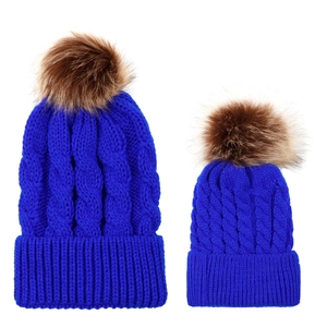 Detail of blue knitted beanies in parent-child set with fluffy faux fur pom-poms