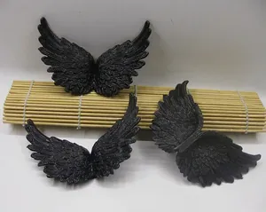 Detail of 3 black plastic angel wings with feather texture for DIY cake toppers