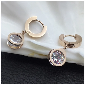 Macro shot of rose gold hoop earrings with round clear zircon on white shell and leather