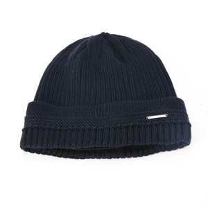 Detail of navy knit beanie showing vertical ribbed texture and silver metal tag