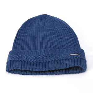 Macro detail of navy blue knit beanie showing thick ribbed texture and metal tag accent