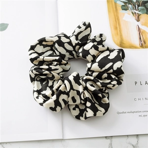 Detail of soft leopard print satin scrunchie on marble background with smooth texture