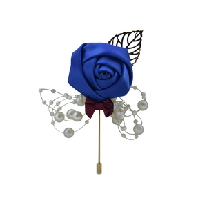 Detail of royal blue ribbon rose brooch with wine red bow and golden leaf accent