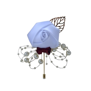 Close-up of white satin rose boutonniere with dark red bow and pearl accents