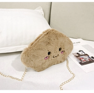 Close-up of light brown plush cloud bag with embroidery and gold chain strap on sofa