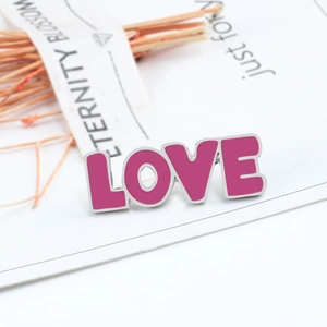 Macro view of a pink enamel LOVE brooch with silver borders on a gift card background