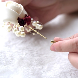 Detail of handmade wedding boutonniere featuring silk roses and pearl accents with safety pin