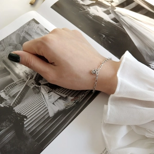 Detail of S925 silver smiley face and tassel charm bracelet worn on a female wrist