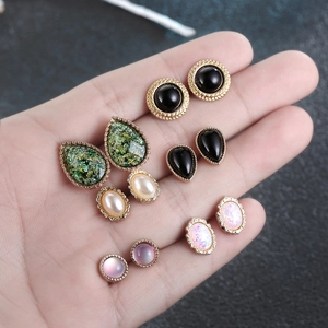 Macro detail of five pairs of vintage gold-framed resin earrings with cat-eye and pearls