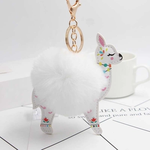 Detailed view of white alpaca keychain with soft faux fur pompom and golden metal clasp