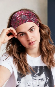 Detail of bohemian floral elastic headband in burgundy fabric worn by a model