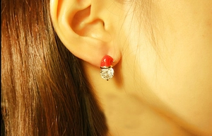 Macro shot of snowman hat earring with red enamel and sparkling zircon on model ear