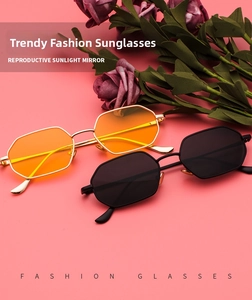 Flat lay of octagon sunglasses in gold with orange lenses and classic black metal frames