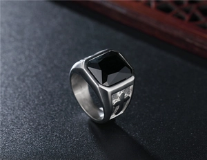 Macro shot of punk signet ring featuring a square black gem and engraved cross