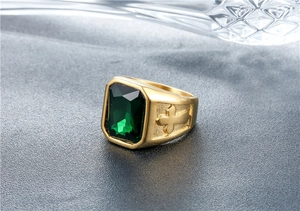 Detail of vintage gold ring with emerald gemstone and embossed cross engraving
