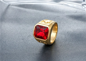 Macro view of gold punk ring featuring a square red gemstone and cross carvings