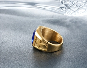 Detail of men's gold ring showing blue gemstone and engraved cross on the side band