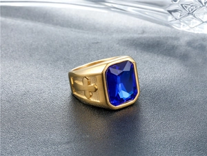 Macro detail of men's gold ring with rectangular blue gemstone and cross carvings