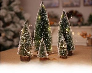 Detailed view of mini frosted Christmas trees with warm LED lights and wooden bases