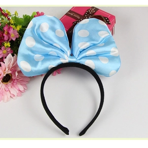 Blue polka dot satin bow headband with decorative flowers and gift box background