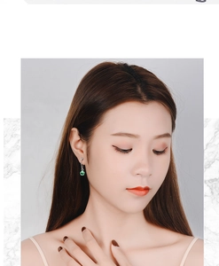 Macro detail of silver chain earring with green four-leaf clover crystal on model