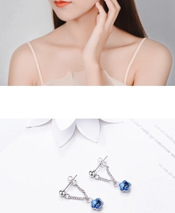 Detail view of silver floral earrings with blue crystal charms shown on a model