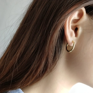 Close-up of polished 925 sterling silver hoop earrings in gold finish worn by a model