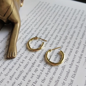 Detail of 925 sterling silver golden hoop earrings on a vintage fashion book background